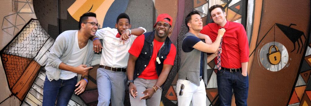Group of men smiling and laughing in front of graphic design wall