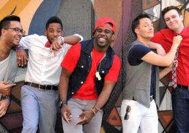 Group of men smiling and laughing in front of graphic design wall